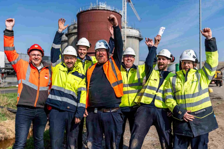Mannen van het projectteam in veiligheidshelmen en vesten voor de realisatie van de vergister