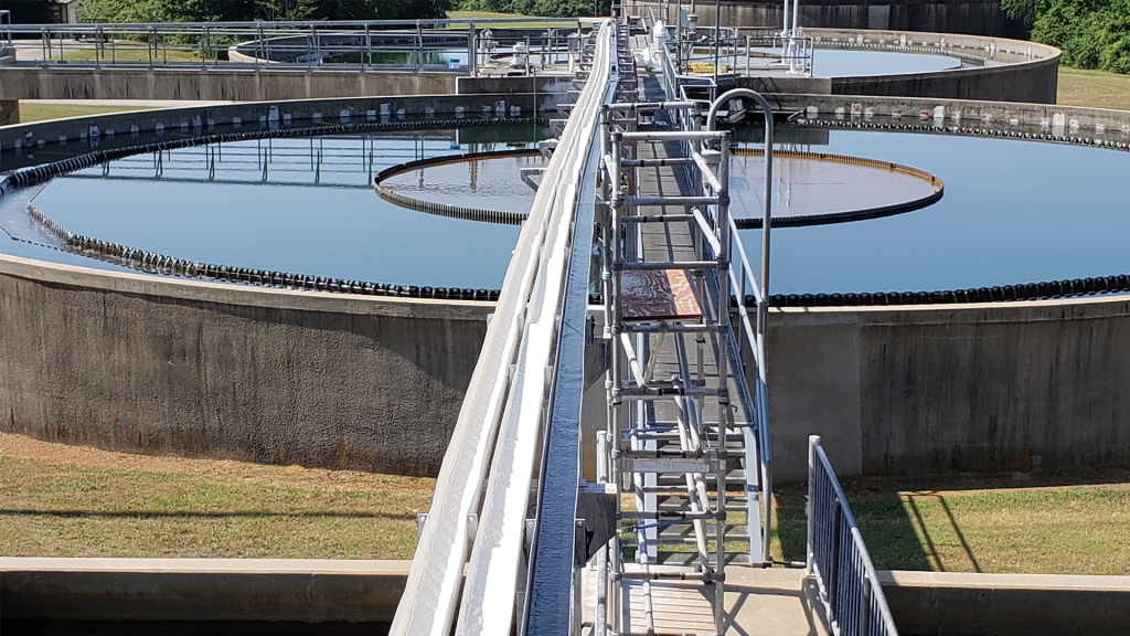 Afvalwater zuivering. Een grote waterzuiveringsinstallatie met een omvangrijke tank in het midden van het terrein.