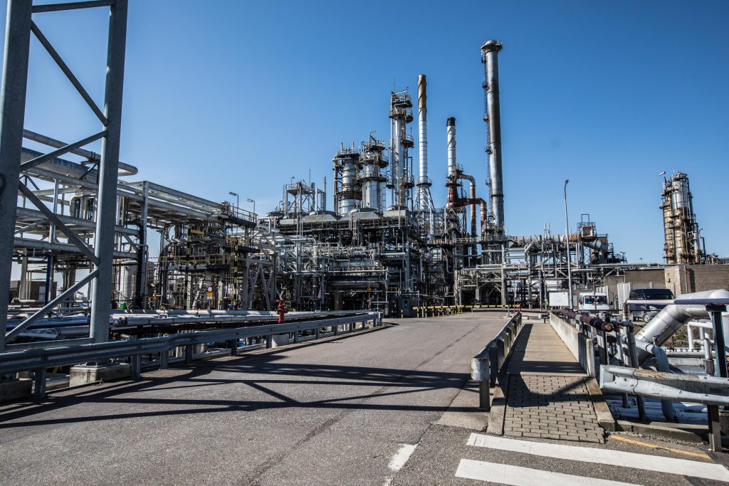 Een grote industriële raffinaderij met veel leidingen en buizen die de faciliteit verbinden.